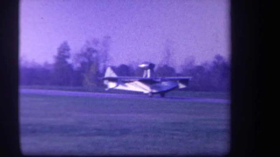 Side view of a small pontoon-equipped airplane moving low over grass in the supplied 1959 Yucaipa home-movie footage.