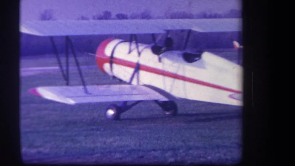 1959 home-movie frame from the Yucaipa area showing the biplane side-on, with wings, struts, cockpit area, and landing gear visible.