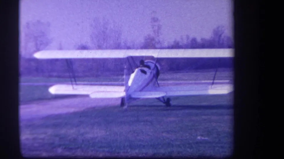 A centered rear angle shows the white biplane parked under its upper wing at the 1959 Yucaipa airfield.