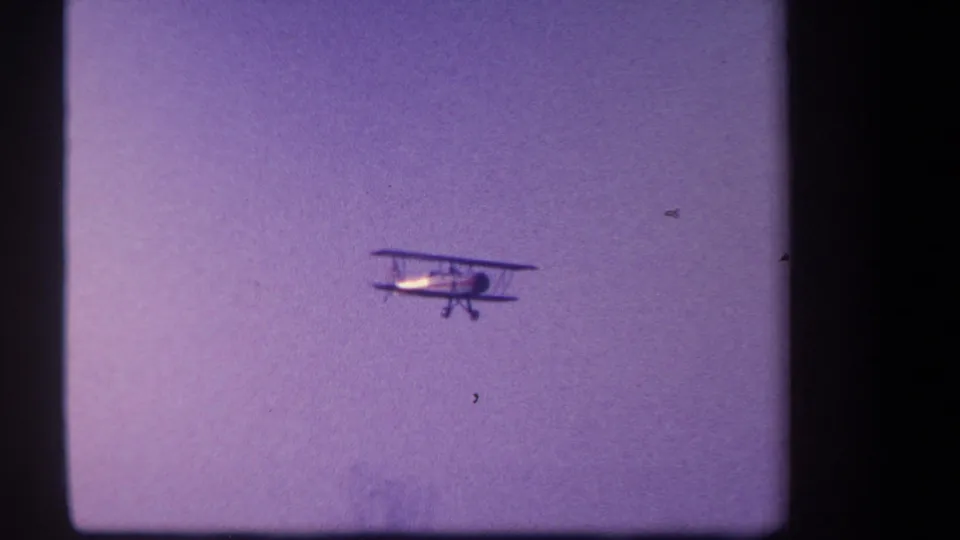 A closer profile of the biplane shows its dual wings and landing gear against the purple-tinted sky.
