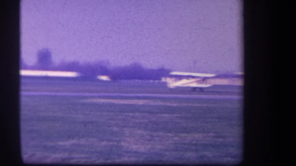 1959 Yucaipa-area home-movie frame showing the small prop plane rolling along the grass runway after landing.