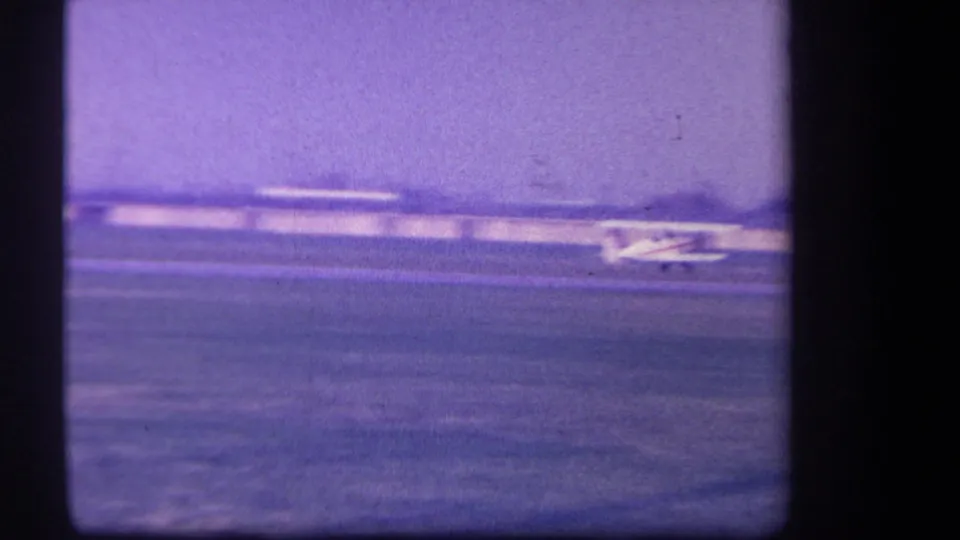 1959 Yucaipa-area frame with the small plane continuing along the grass runway, partly near the edge of the shot.