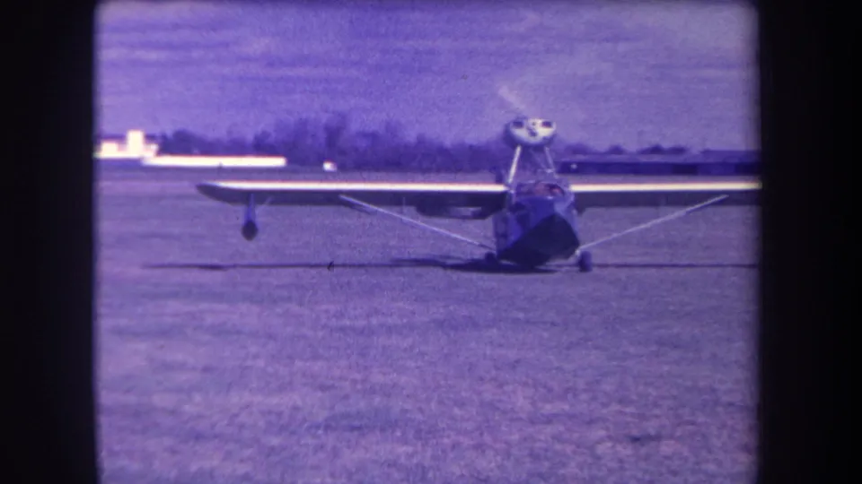 1963 Yucaipa home-movie frame showing a small high-wing propeller aircraft facing the camera on a grass field.