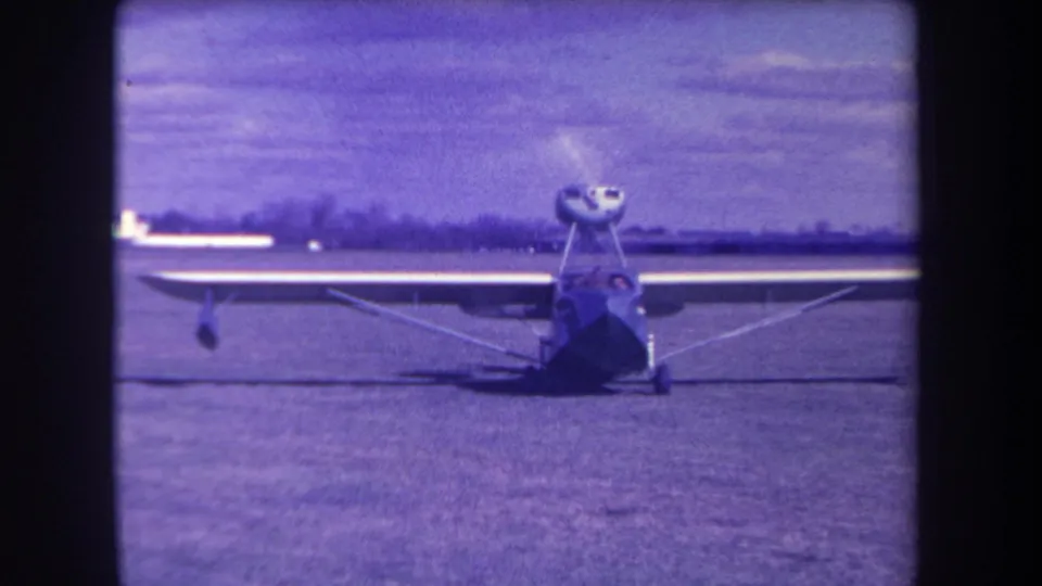 Aged 8mm frame from Yucaipa showing the light aircraft on a grass airfield, with wing struts and cockpit area visible.