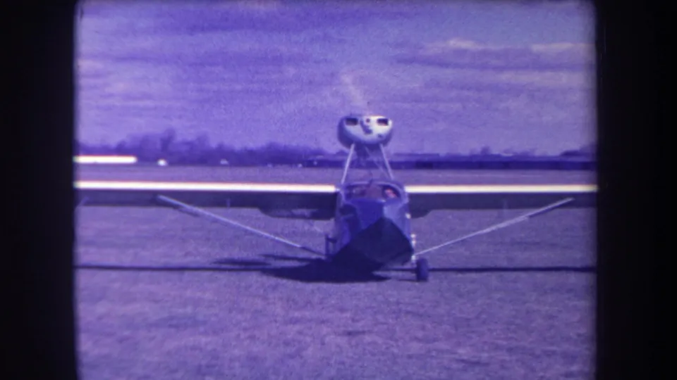 1963 Yucaipa home-movie frame showing the small propeller aircraft front-on, with landing gear, wing struts, and aged color cast.