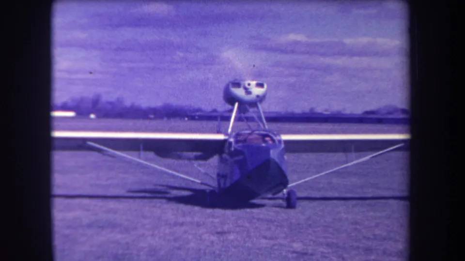 1963 Yucaipa-area home-movie frame showing a small blue amphibious aircraft facing forward on a grass airfield.