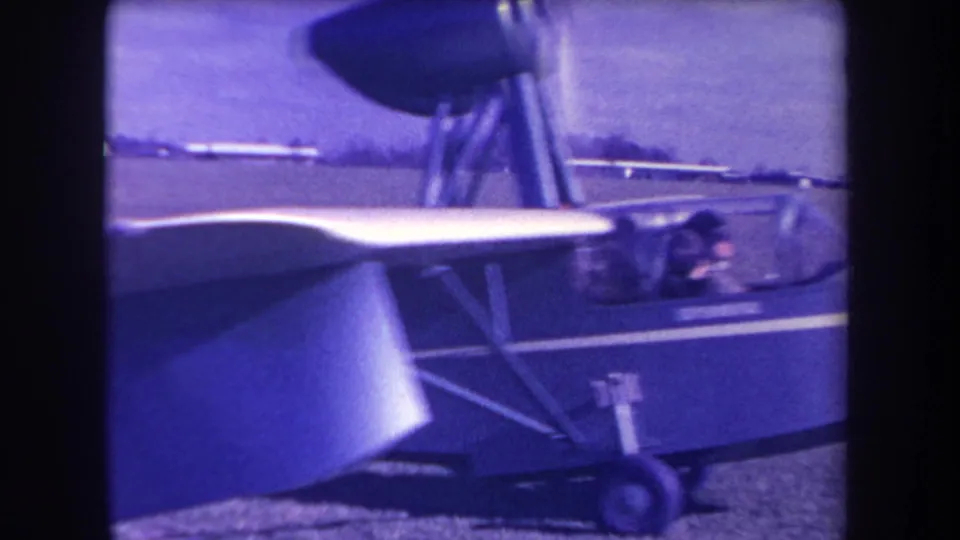 Close 1963 airfield frame showing the amphibious aircraft's wing, fuselage side, cockpit area, and wheel assembly.