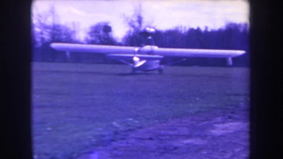Final frame of the 1963 Yucaipa clip showing the long-wing aircraft low on the grassy field with trees beyond.