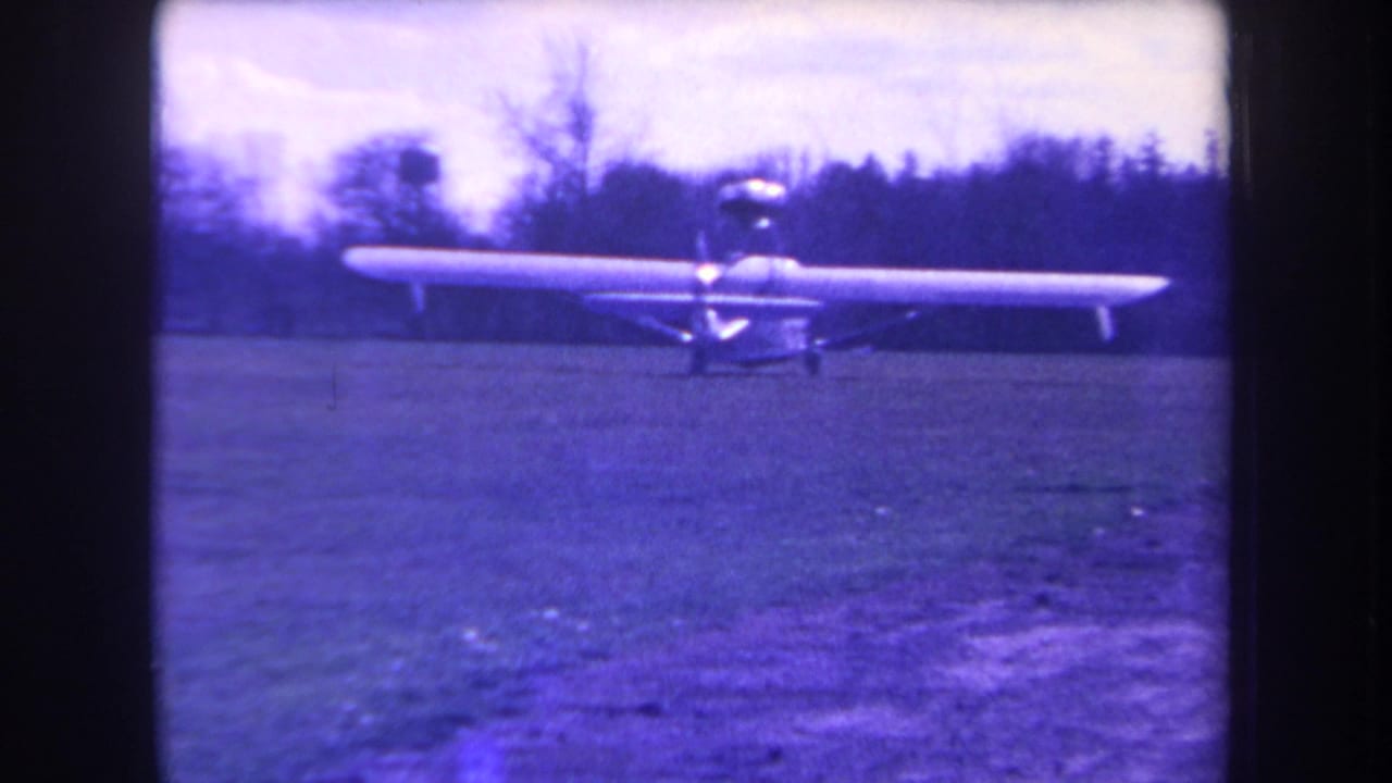 A small propeller aircraft remains on a grassy Yucaipa airfield in 1963, with bare trees and aged purple-blue 8mm color visible.