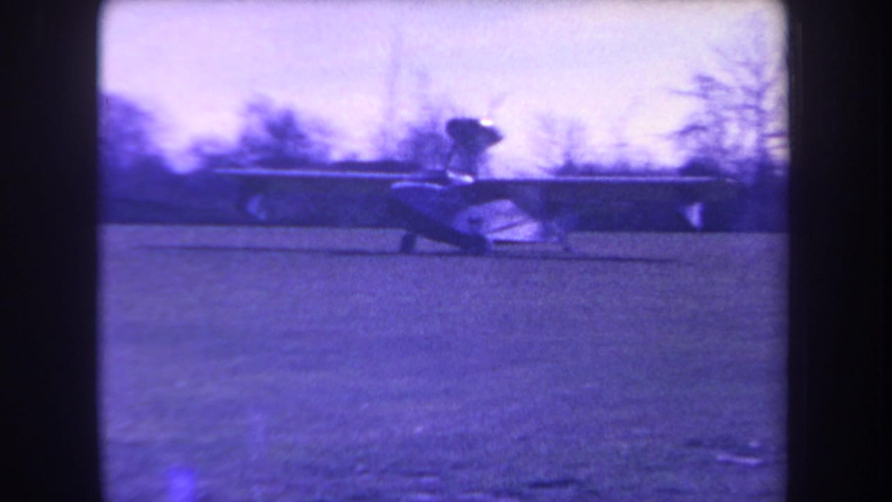 Small aircraft side view on grass, framed by dark contact-sheet borders.