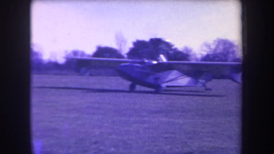 Closer 1963 home-movie view of the small amphibious aircraft on grass, with its wing, fuselage, and landing gear visible.