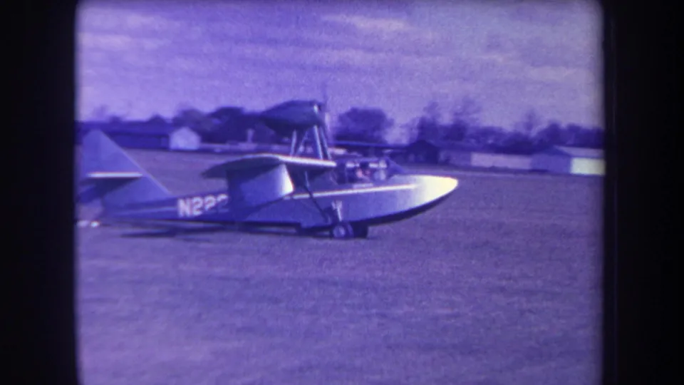 Rear-side view of the small aircraft on grass, with a partial N22 tail marking and possible cockpit occupants not clearly identifiable.