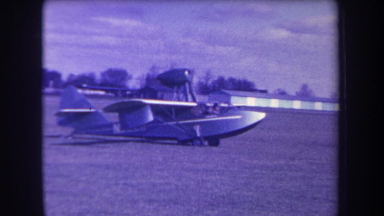 1963 Yucaipa-area home-movie frame showing a small amphibious aircraft in side view on a grass airfield.