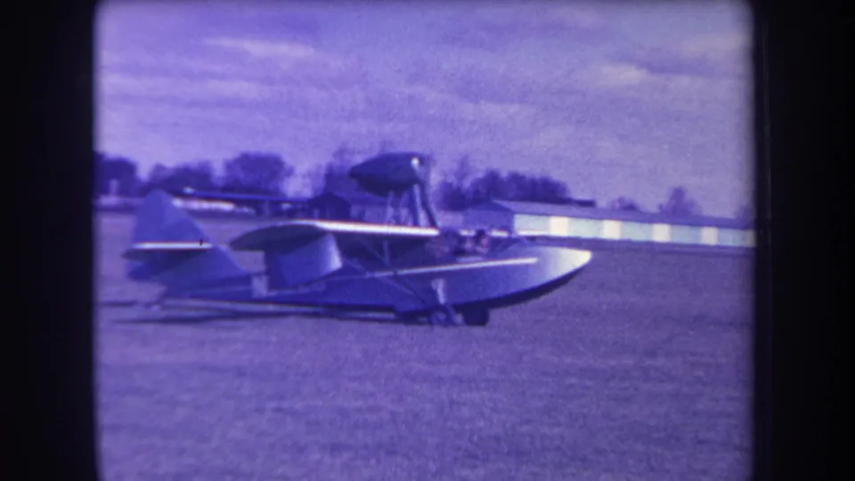 1963 Yucaipa-area home-movie frame showing a small amphibious aircraft in side view on a grass airfield.