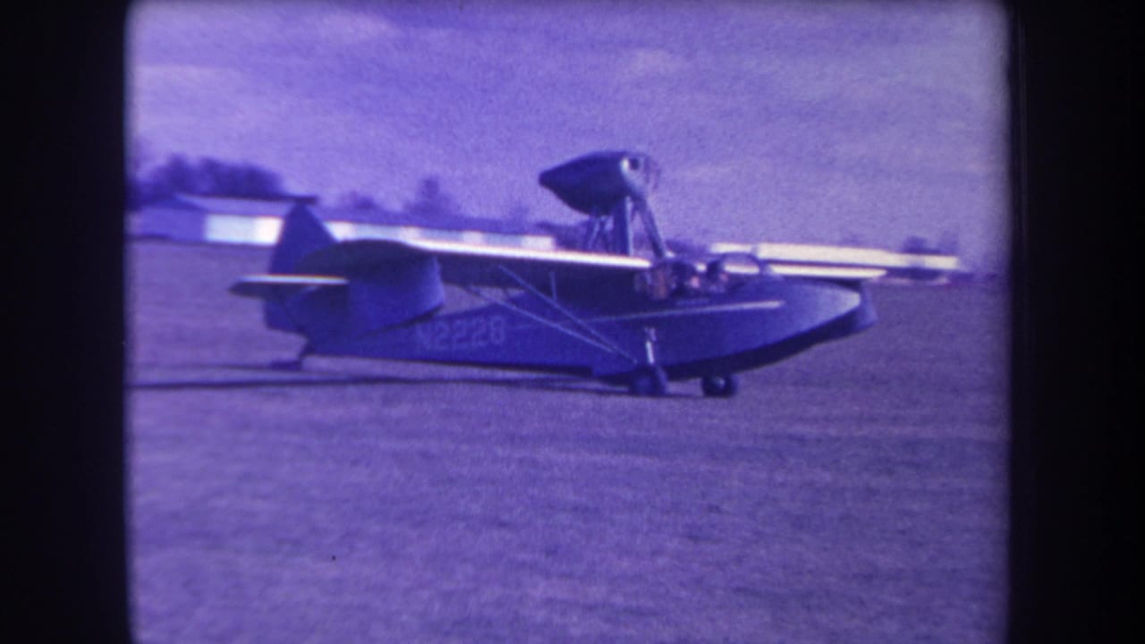 A small amphibious aircraft taxis across a grassy Yucaipa airfield, with markings visible on the fuselage.
