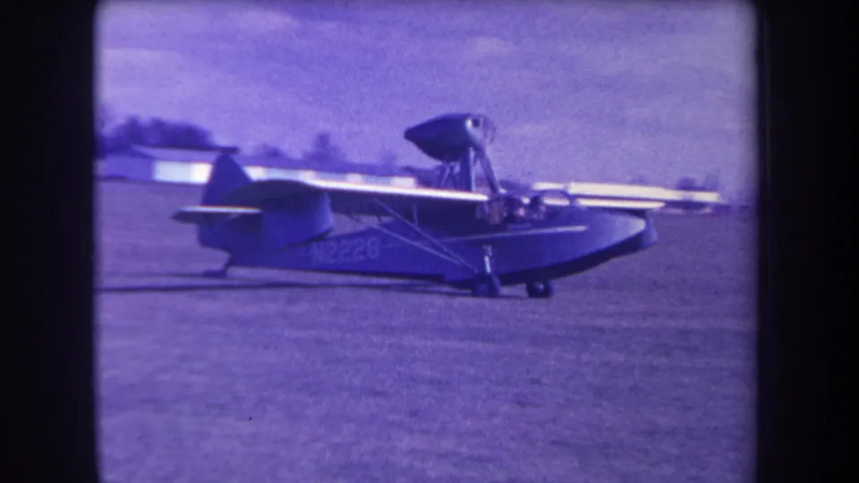 A small amphibious aircraft taxis across a grassy Yucaipa airfield, with markings visible on the fuselage.