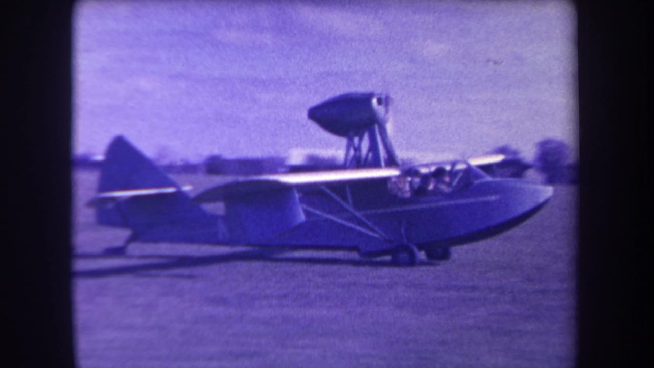 1963 Yucaipa home-movie frame showing a small amphibious aircraft from the side, with people visible in the cockpit and a high-mounted propeller pod.