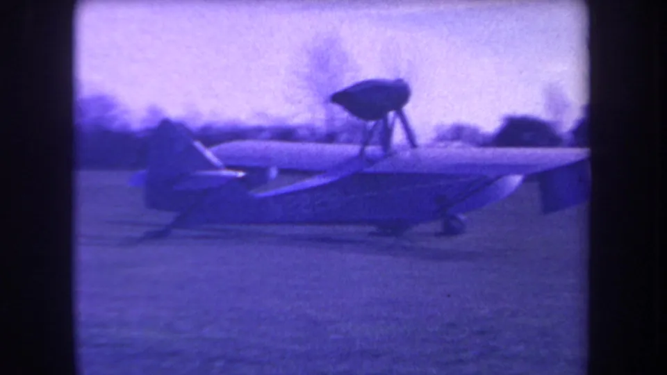 Small single-engine aircraft appears on a grassy Volmer Yucaipa field in purple-blue 8mm footage from 1963.