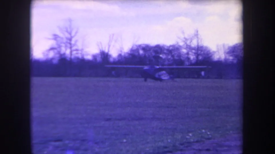 A small single-engine aircraft crosses the grass field in this 1963 Yucaipa home-movie frame.