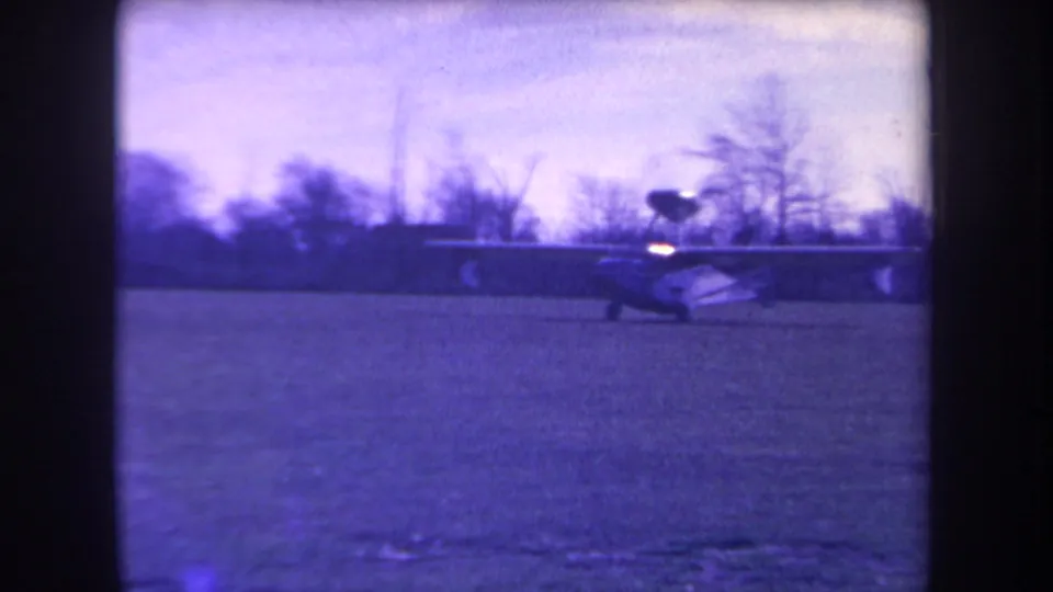 A small aircraft is seen near the edge of the frame on a grassy California airfield in 1963 home-movie footage.