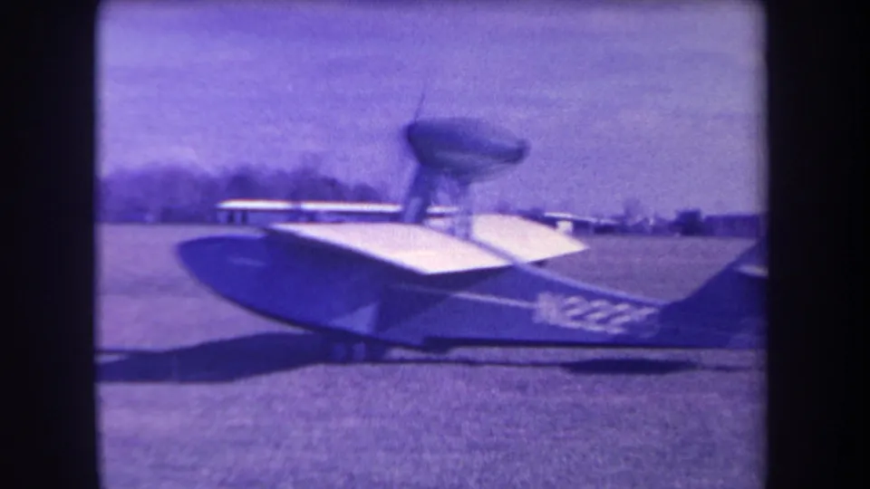 Closer 1963 8mm frame of the amphibious aircraft body, wing, and tail area on grass at the Yucaipa airfield location.