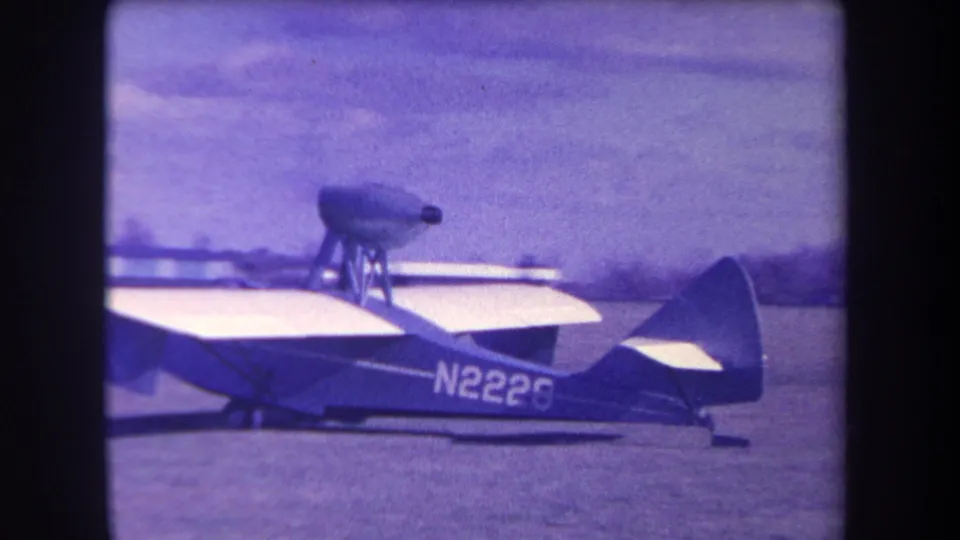 Profile view of the 1963 Yucaipa amphibious aircraft with N2226 visible, set against a grass field and distant low hills or trees.