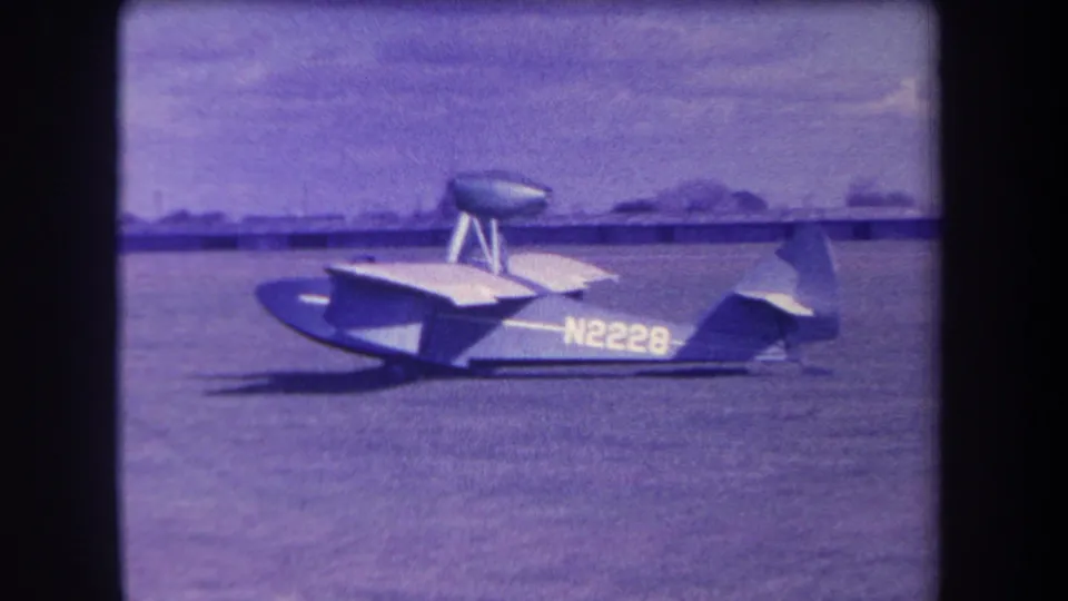 Side-profile 8mm frame of the N2228 aircraft on a grass field in the 1963 Volmer Yucaipa home-movie clip.