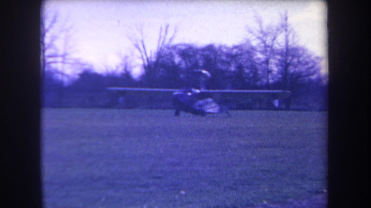 Blue-tinted 8mm frame of a small light aircraft on a grassy field in Volmer Yucaipa, California, in 1963.