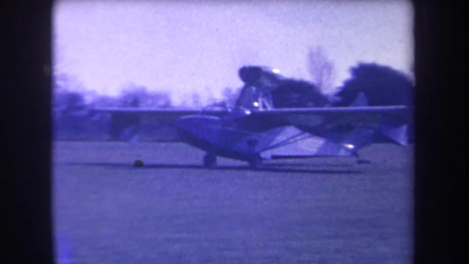 A closer 1963 home-movie view shows the single-engine plane moving across the grassy airfield area.
