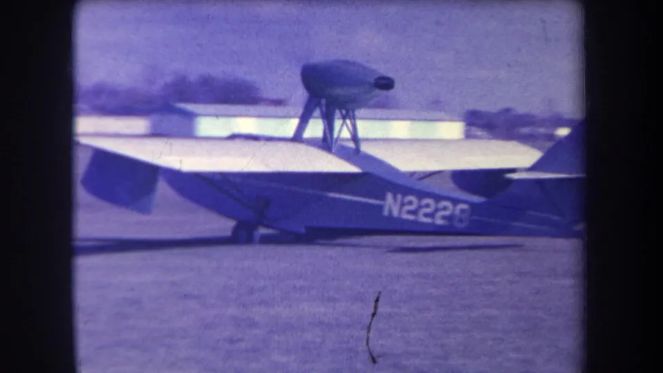 1963 Yucaipa-area home-movie frame showing a small airplane marked N2226 on grass with soft purple film color and airfield structures behind it.