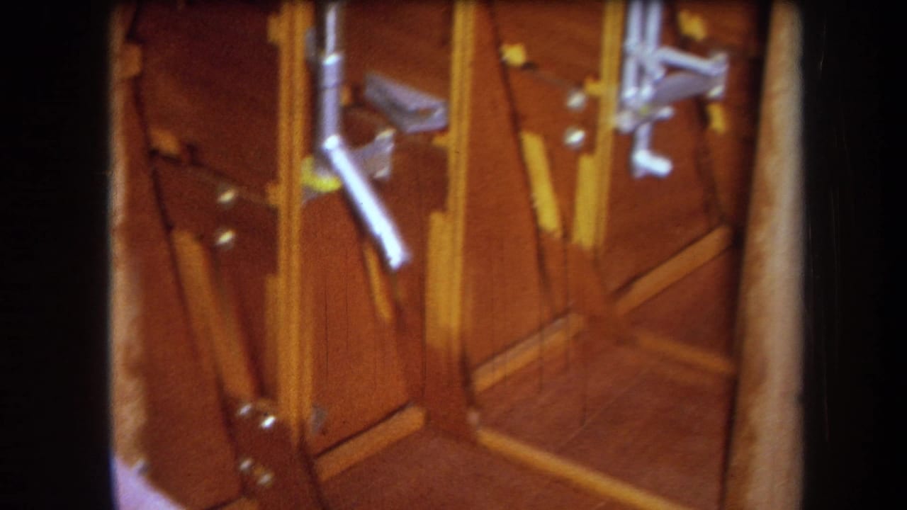 Close 8mm frame of a wood-paneled interior surface with angled trim, small metal fixtures, and warm brown color shift.