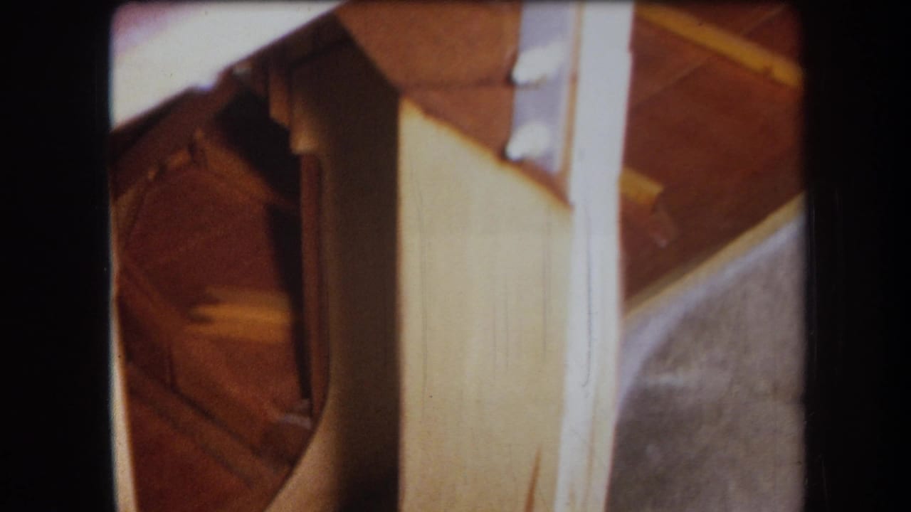 1964 Yucaipa home-movie frame showing interior joinery with pale wood, darker support pieces, a metal bracket, and soft 8mm focus.