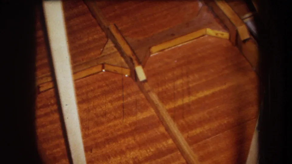 Final frame shows a close view across a wooden surface with small loose wood pieces and a pale vertical edge, consistent with damage inspection.