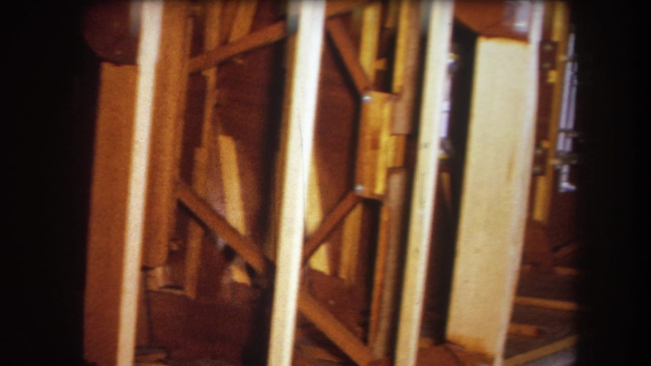 Handheld 1964 Yucaipa footage frame showing amber-toned interior framing and close wooden structural supports.