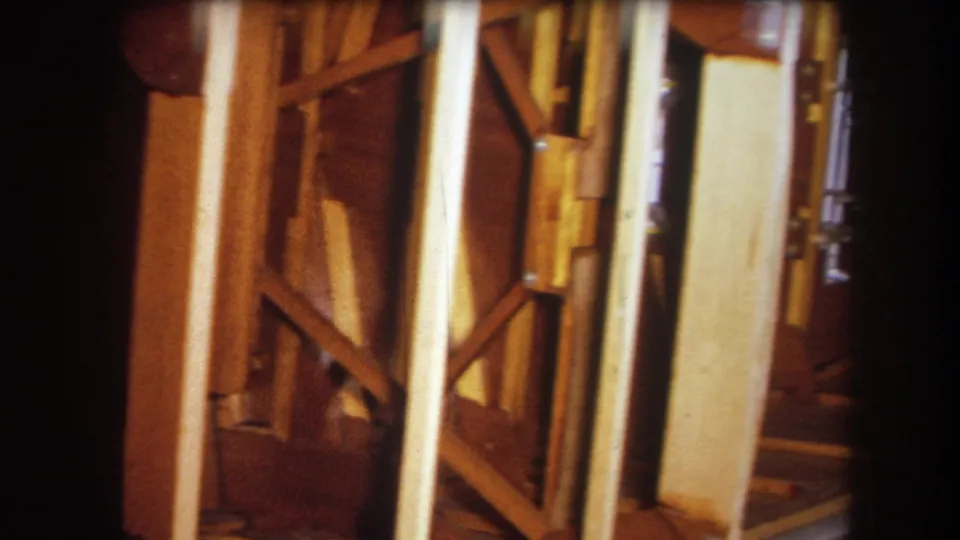 Handheld 1964 Yucaipa footage frame showing amber-toned interior framing and close wooden structural supports.