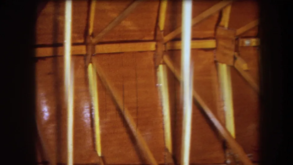 Warm 8mm frame of an unfinished wooden interior in Yucaipa, with diagonal supports, vertical streaking, and dark contact-sheet borders.