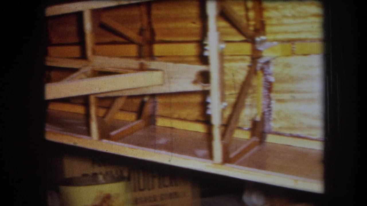 1964 Yucaipa home-movie frame showing a partly built wooden boat frame with braces, planking, and exposed joinery.