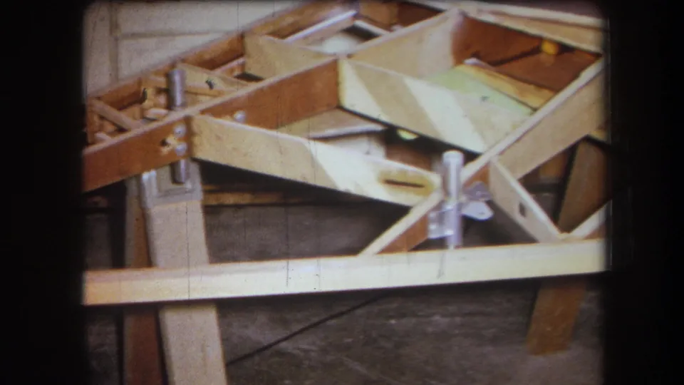 1964 Yucaipa frame showing a close view of wooden boat construction, with braces, fasteners, and pale unfinished planking.