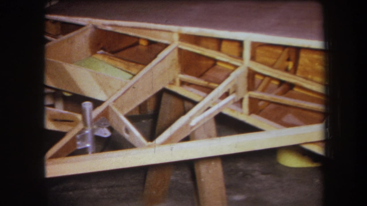 1964 8mm workshop view in Yucaipa showing a wooden frame section with diagonal braces, crosspieces, and a metal bracket.