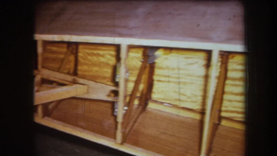 1964 8mm frame from Yucaipa showing the end of a wooden wall frame with vertical supports, panel backing, and visible hardware.