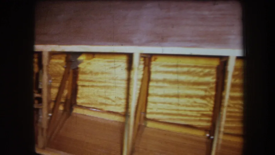 1964 Yucaipa-area home-movie frame showing wood ceiling panels, posts, diagonal bracing, and dark 8mm gate edges.