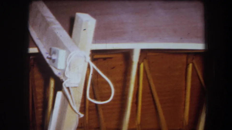 Close 1964 Yucaipa-area home-movie view of a white-painted brace with a looped cord shape beside wood ceiling framing.