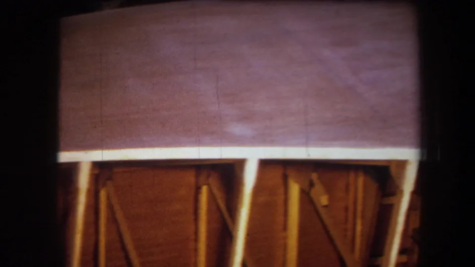 1964 Yucaipa-area home-movie frame showing a broad wood ceiling surface above exposed posts and diagonal support members.