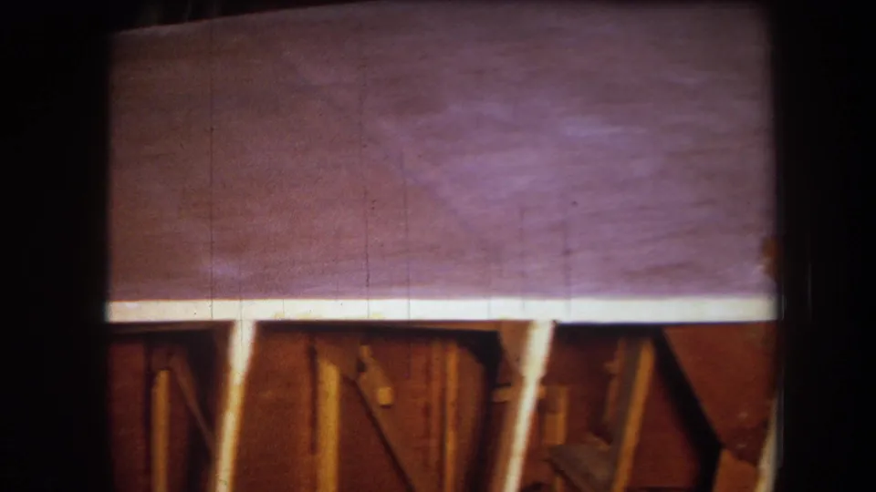 1964 8mm frame from Yucaipa showing a purple-tinted wooden surface with exposed framing and vertical supports below.