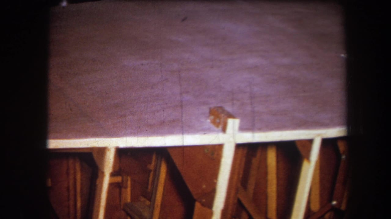 1964 Yucaipa home-movie frame showing the wooden structure from a slightly shifted angle, with a small cable or object near the upper edge.