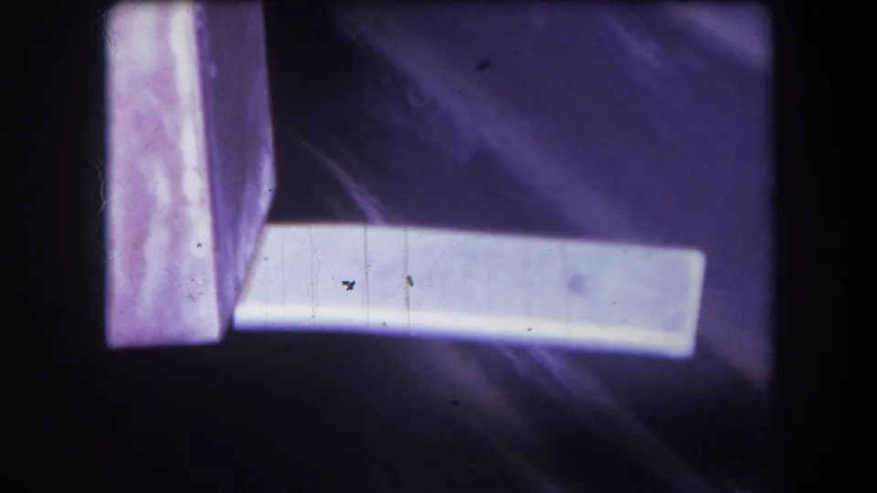 Tight 8mm view from 1964 Yucaipa showing a white rectangular object projecting from a vertical corner edge amid purple color shift.