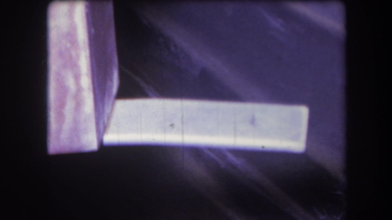1964 Yucaipa home-movie frame with a white plank extending across a purple-tinted surface, visible grain, dust, and edge darkening.