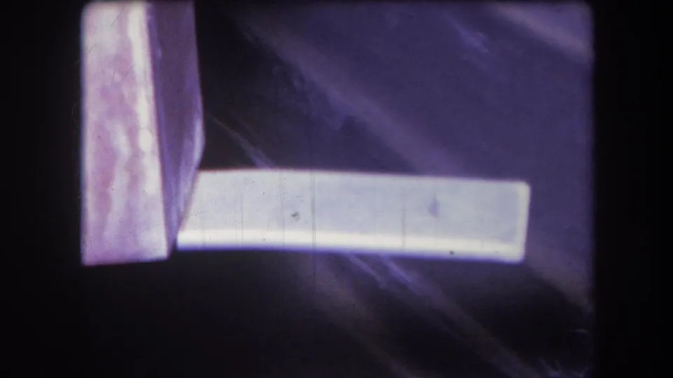 1964 Yucaipa home-movie frame with a white plank extending across a purple-tinted surface, visible grain, dust, and edge darkening.
