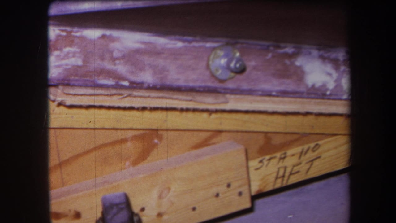 1964 Yucaipa-area 8mm frame showing wood construction framing, a purple-painted metal beam, bolt hardware, and handwritten station markings.