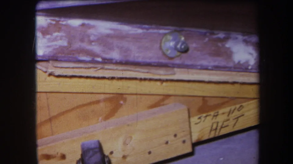 Final frame of the 1964 Yucaipa 8mm clip, centered on wood framing, purple-painted metal, a bolt, and the handwritten STA-110 AFT notation.